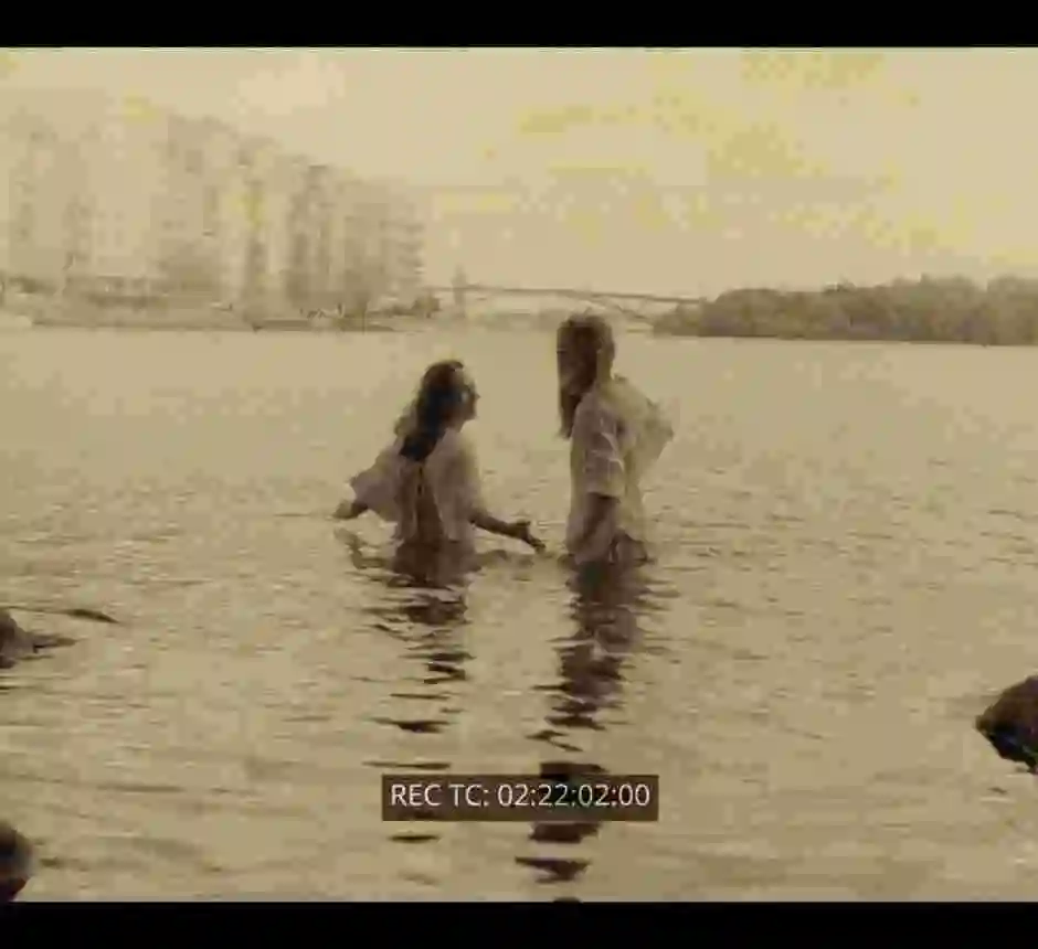 Två kvinnor badar i sjön Mälaren med hus i fonden.