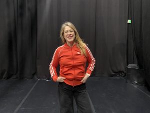 En foto på dansaren Angela Wand i röd tröja i en black box.