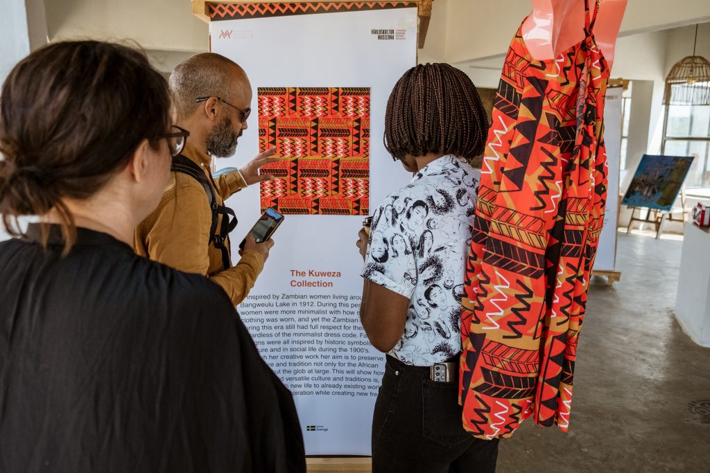 Persons standing infron of textile art piece